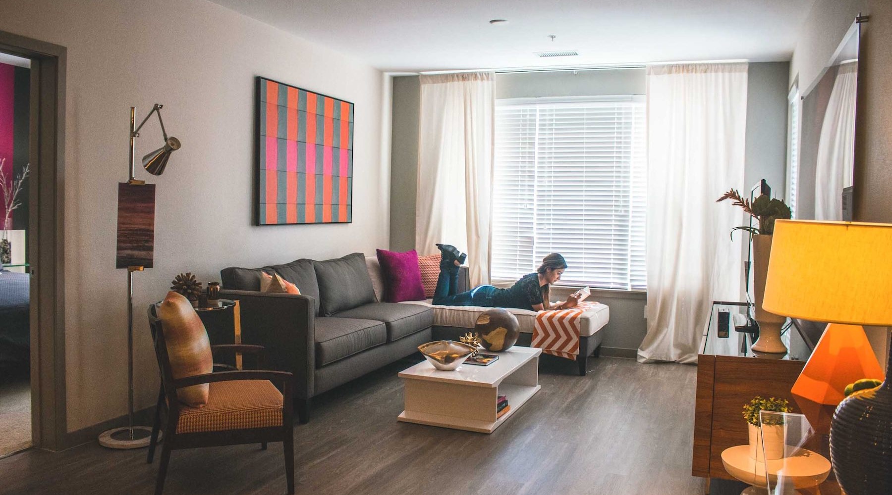 living room with someone laying on a couch reading a book
