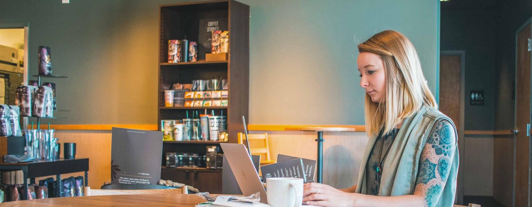 a woman sitting at a table looking at a laptop